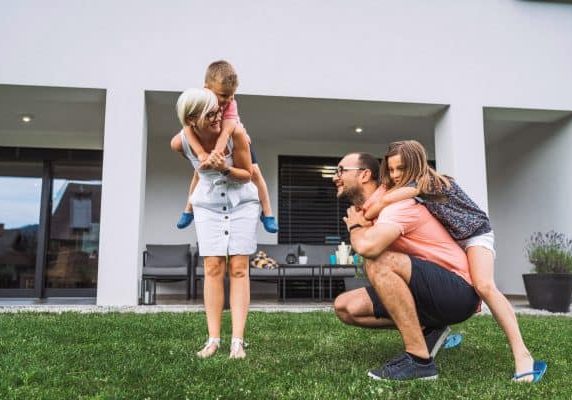 Happy caucasian family of four, mother father and children at home, outdoors playing on the grass, and indoors in the living room having fun as a family.