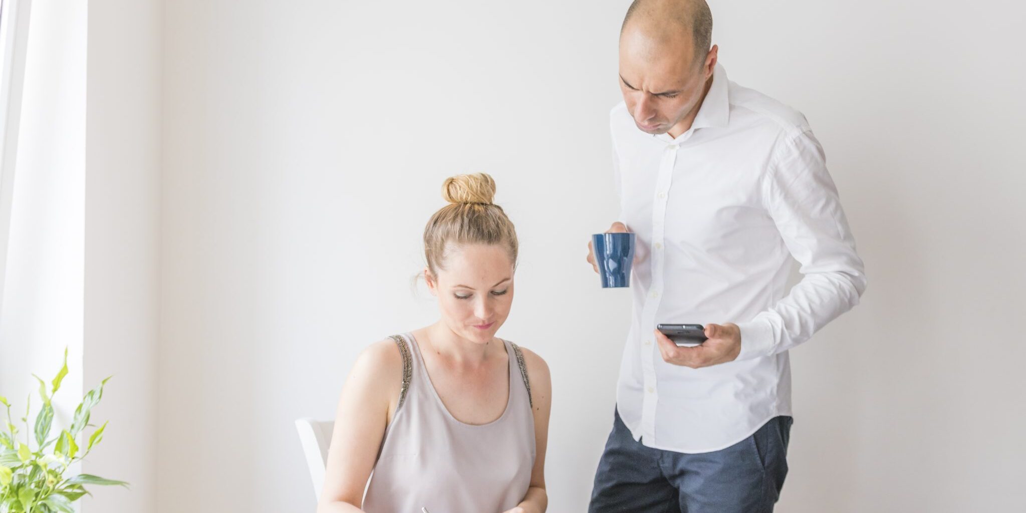 businessman-holding-calculator-coffee-cup-looking-woman-writing-diary